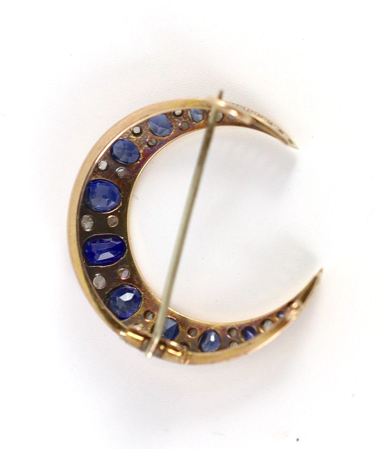 An Edwardian gold and graduated oval cut sapphire and rose cut diamond set crescent brooch